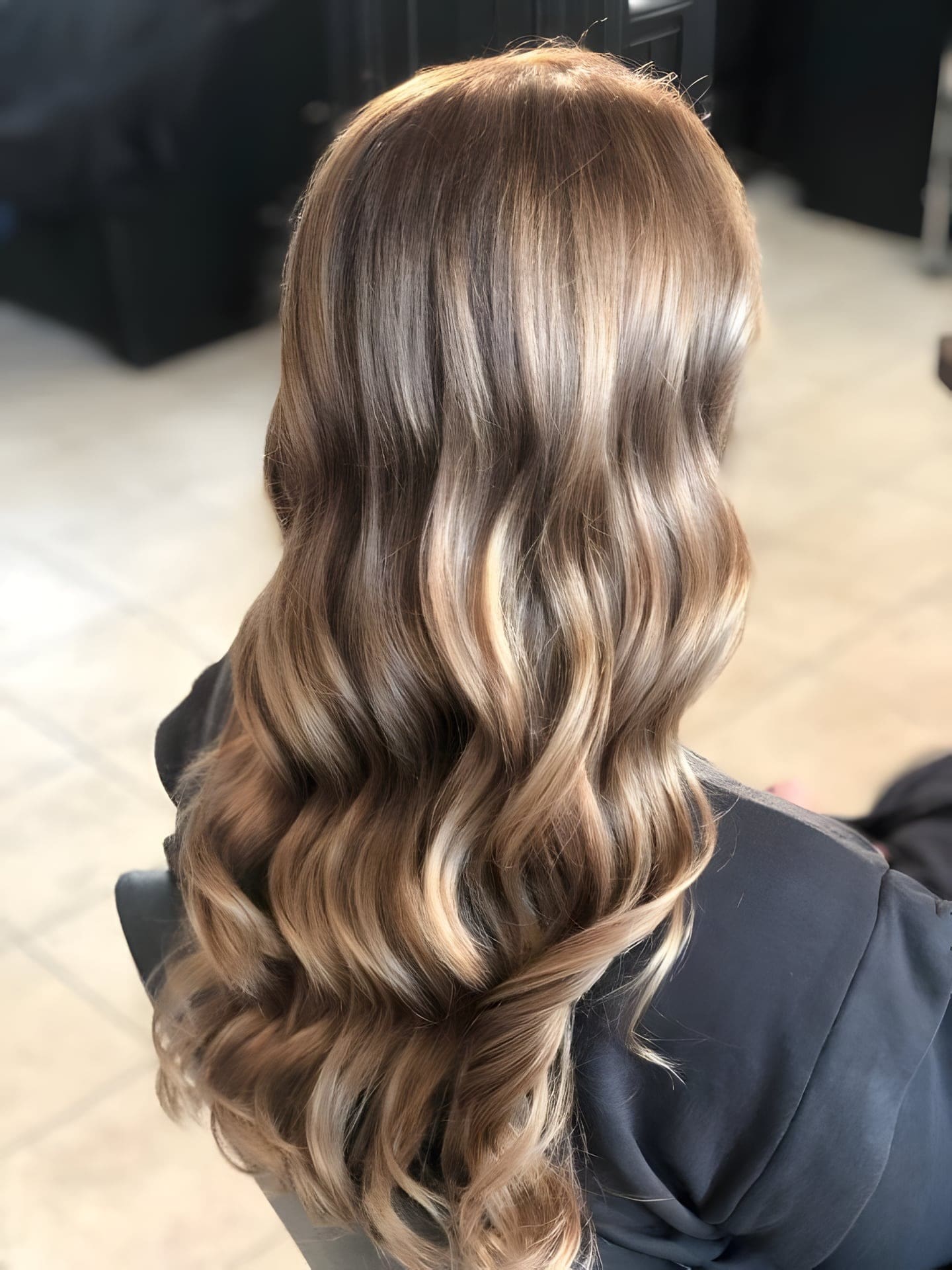 Lang blond haar met highlights in losse golven, gefotografeerd in de salon.