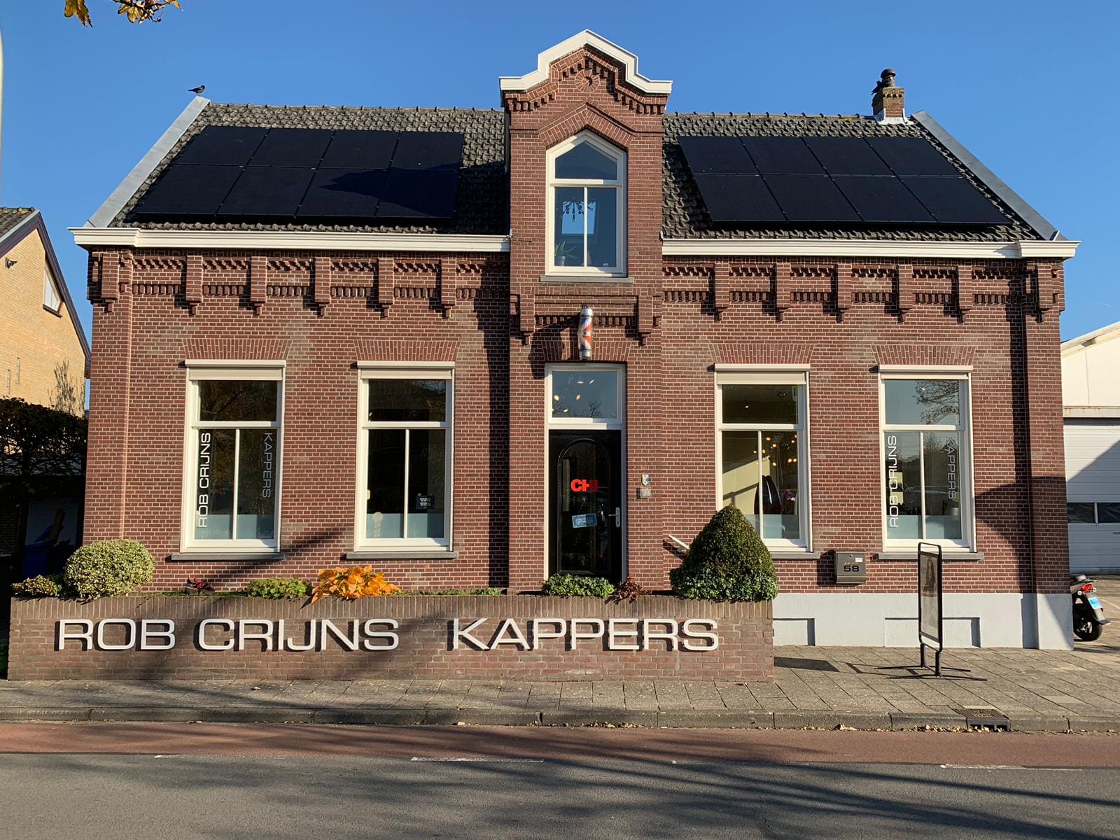 De gevel van Rob Crijns Kappers aan de Dijkshoornseweg 58 in Den Hoorn, met de naam in witte letters op het muurtje.
