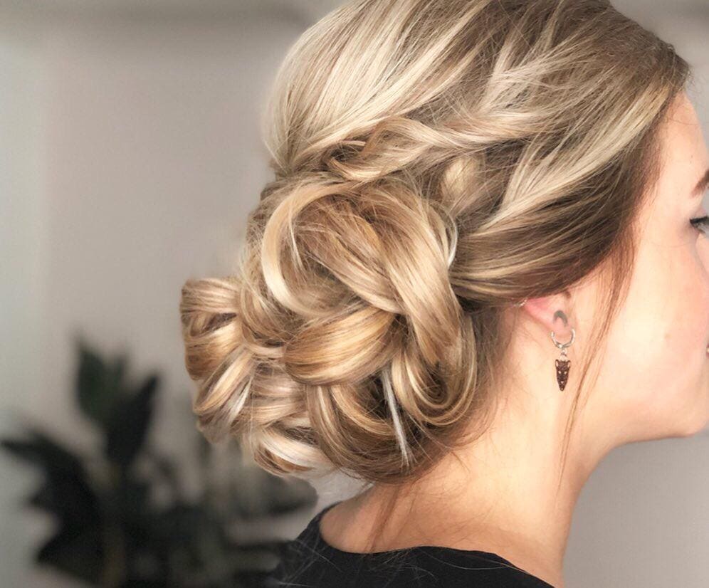 Opgestoken kapsel met gedraaide blonde lokken in de nek.