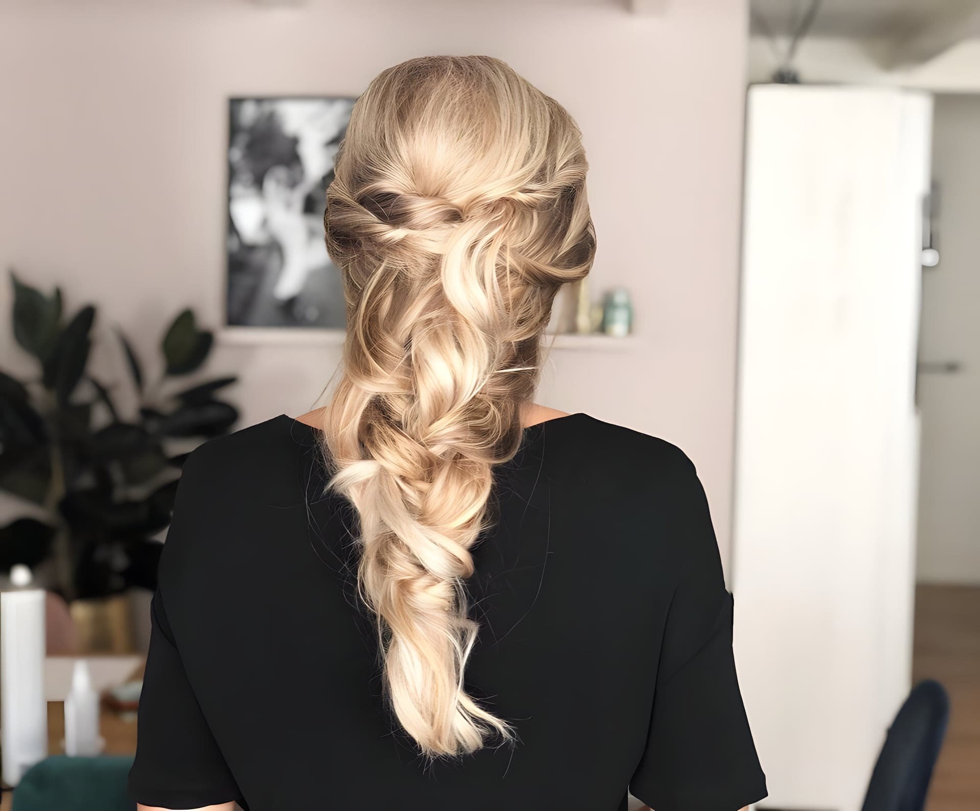 Losse blonde vlecht met uitgetrokken lokken, gefotografeerd in de salon.